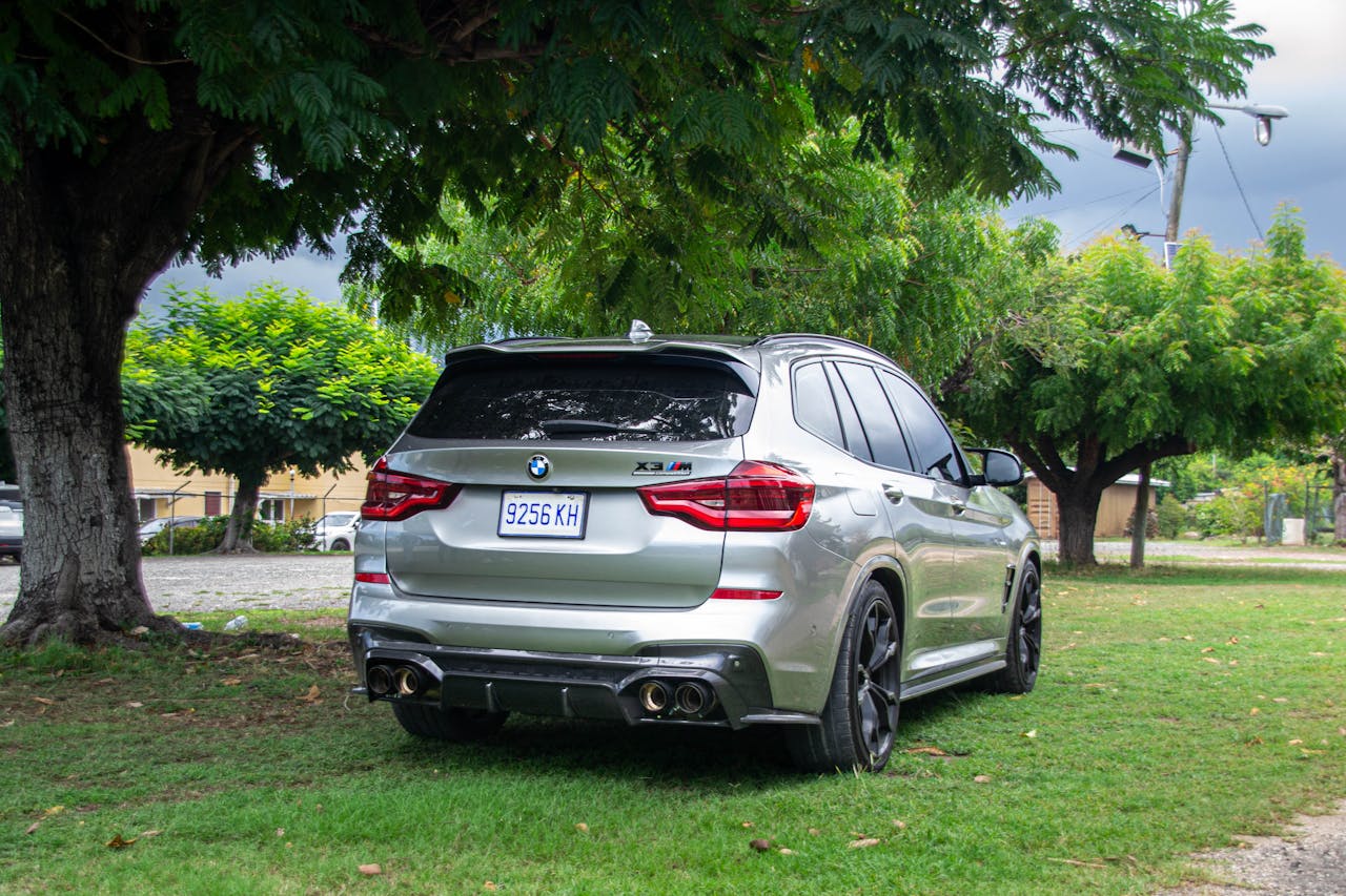 A silver SUV parked on a lawn surrounded by lush green trees, showcasing a peaceful setting.